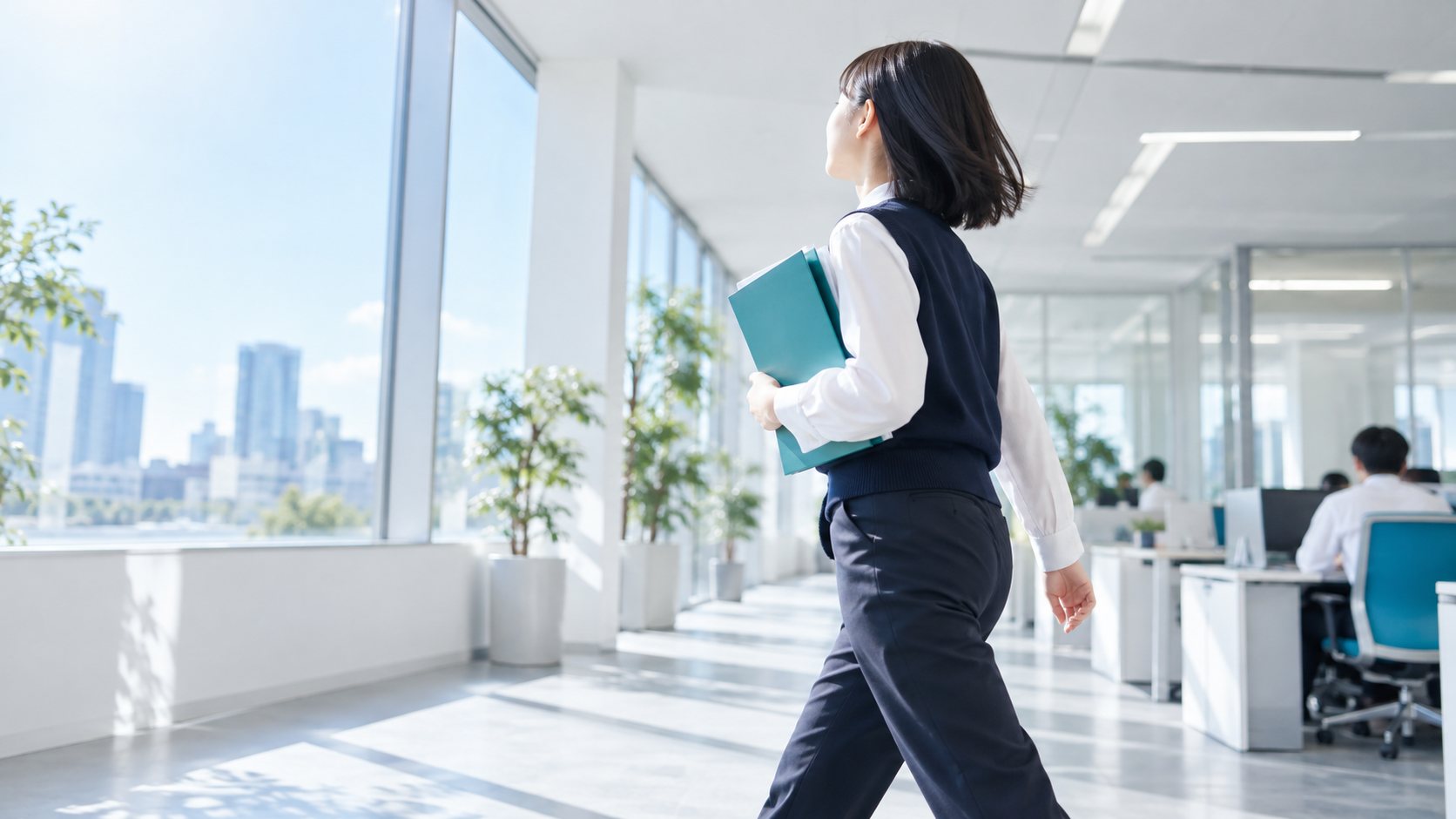 書類を抱えてオフィスを歩く新人の事務スタッフ